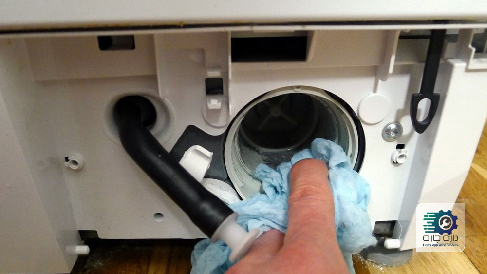 یک نفر در حال تمیز کردن ظرف تخلیه ماشین لباسشویی