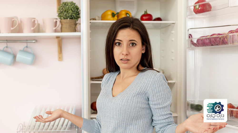 یک نفر تعجب زده و گیج شده جلوی یخچال فریزر ایستاده