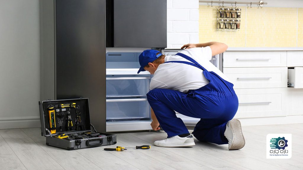یک تعمیرکار در حال تعمیر یخچال فریزر است.
