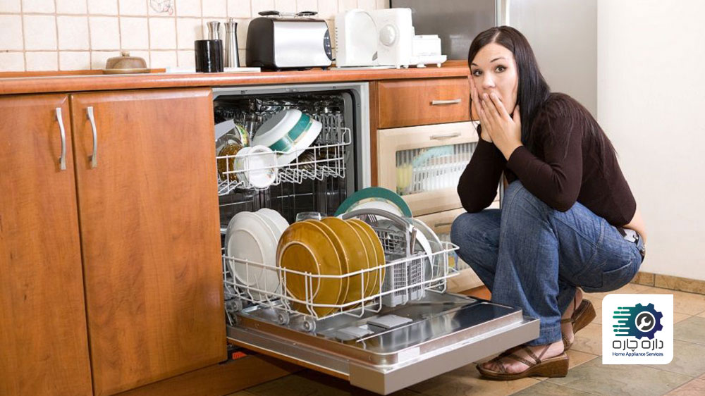 یک خانم که از تجمع آلودگی ها در پشت ماشین ظرفشویی تعجب کرده است