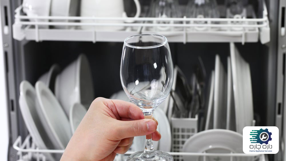 یک نفر در حال نشان دادن لکه های سفید تشکیل شده روی ظروف شسته شده در ماشین ظرفشویی ویرپول