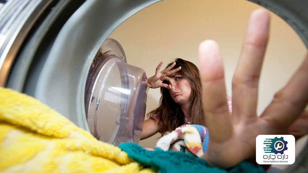 یک خانم که به خاطر بوی بد ماشین لباسشویی نف دماغ خود را گرفته است