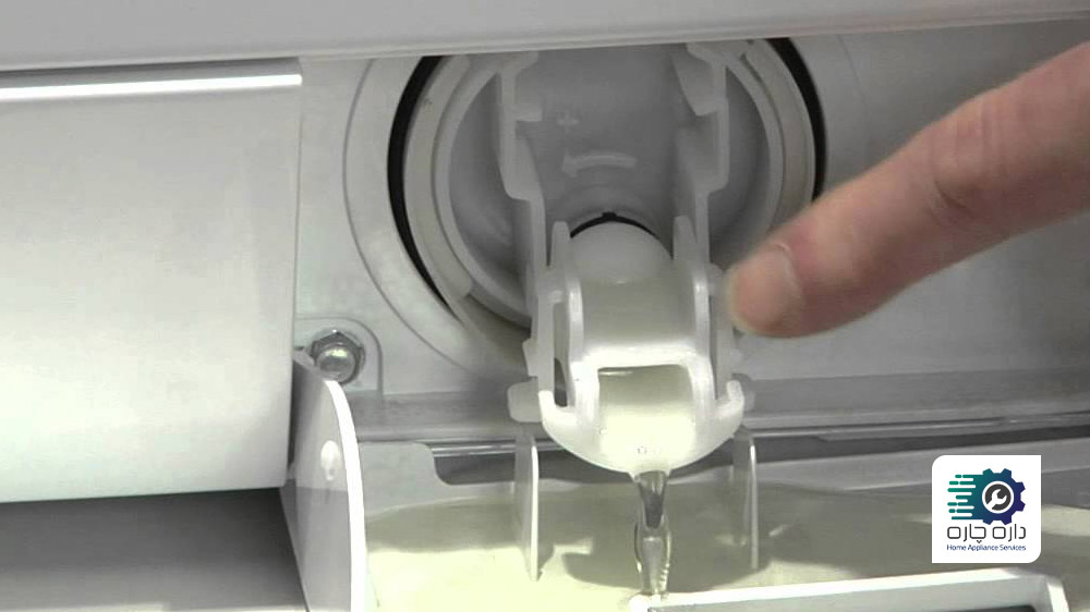 شخصی در حال اشاره به فیلتر تخلیه ماشین لباسشویی آاگ است که آب درون آن در حال خالی شدن است