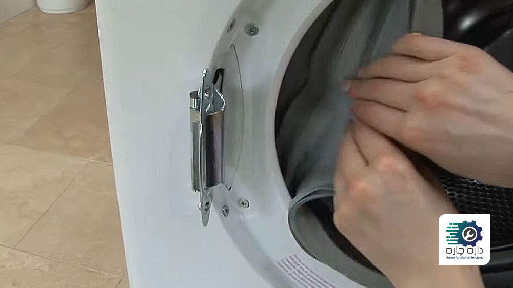 شخصی در حال کنار زدن لاستیک درزگیر درب ماشین لباسشویی آاگ