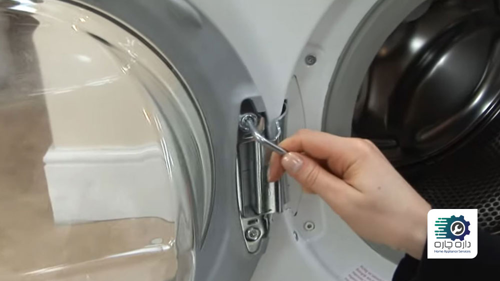 شخصی در حال جدا کردن درب از لولای ماشین لباسشویی آاگ