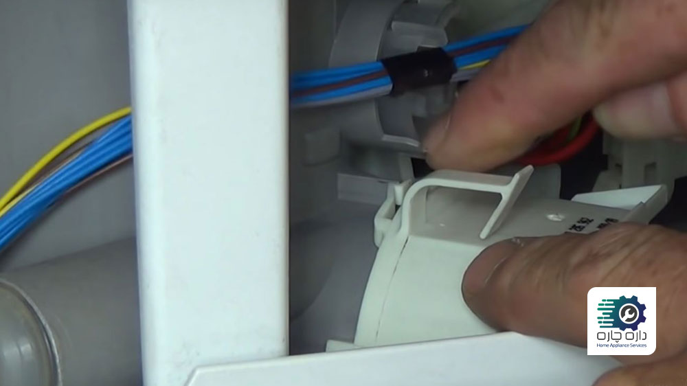 شخصی در حال نصب پمپ تخلیه جدید در ماشین ظرفشویی بوش