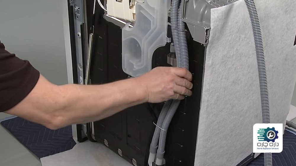 یک نفر در حال نصب شیلنگ تخلیه روی گیره های نگهدارنده ماشین ظرفشویی ال جی