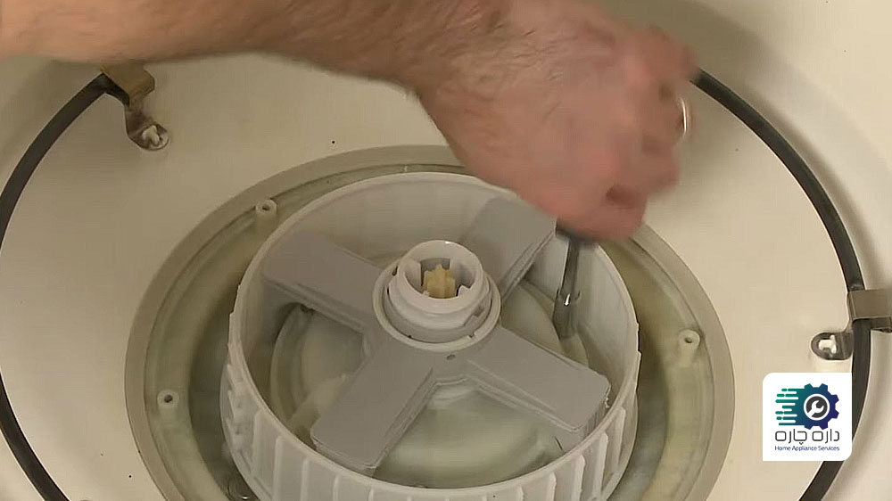 یک نفر در حال نصب مجموعه محفظه پمپ و نگهدارنده بازوی آبپاش ماشین ظرفشویی می تگ