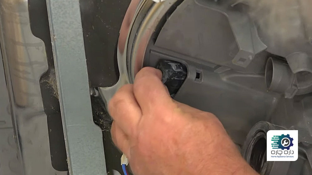 شخصی در حال نصب گیره نگهدارنده موتور سیرکولاتور به کف ماشین ظرفشویی می تگ