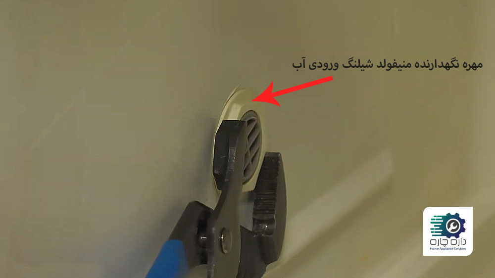 شخصی در حال باز کردن مهره نگهدارنده منیفولد لوله ورودی آب ماشین ظرفشویی Whirlpool به وسیله انبر کلاغی
