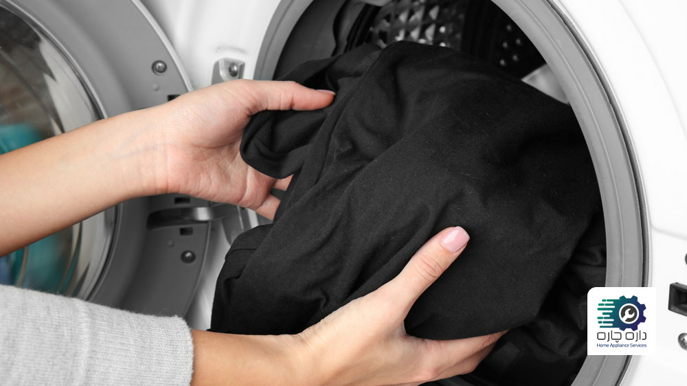 شخصی در حال قرار دادن لباس های مشکی در ماشین لباسشویی