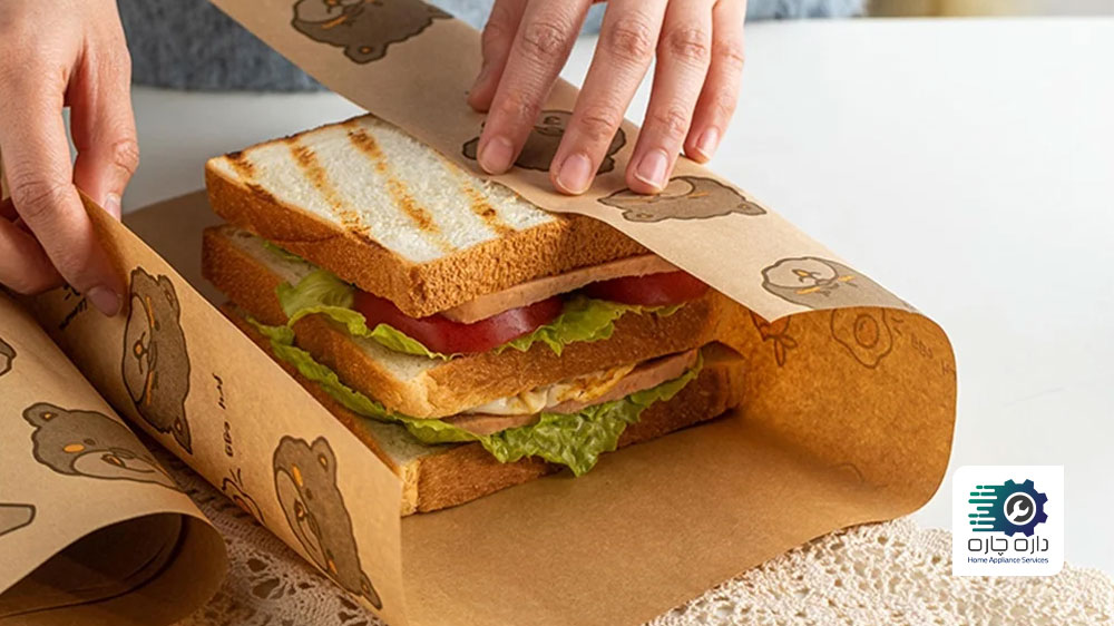 یک نفر در حال پیچیدن ساندویچ در یک کاغذ قهوه ای چاپ شده