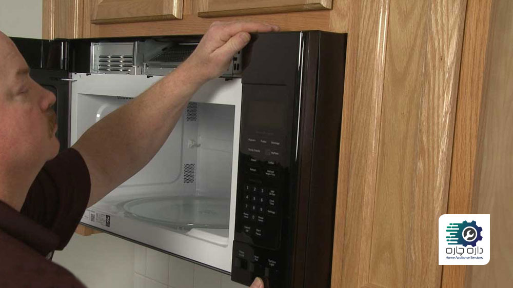 یک نفر در حال تعویض پنل کنترل مایکروفر