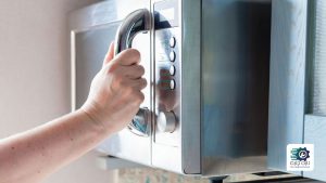 یک نفر در حال باز کردن درب مایکروویو است.