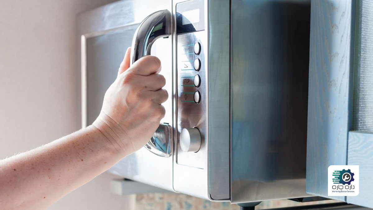 یک نفر در حال باز کردن درب مایکروویو است.