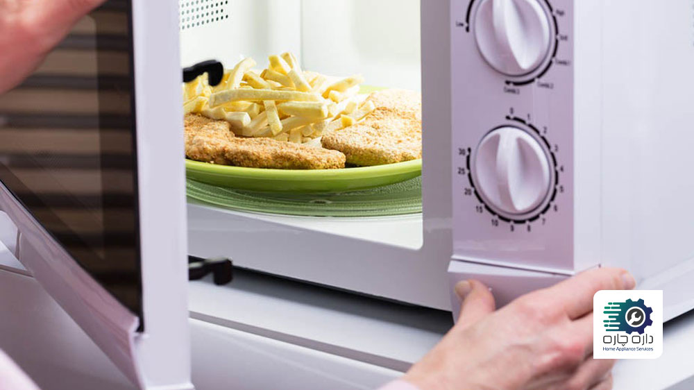 یک نفر در حال فشار دادن دکمه باز کننده درب مایکروویو