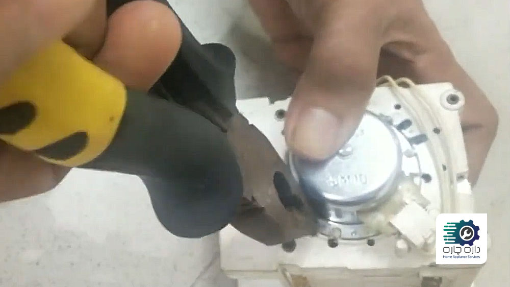 شخصی در حال نصب موتور تایمر جدید ماشین لباسشویی