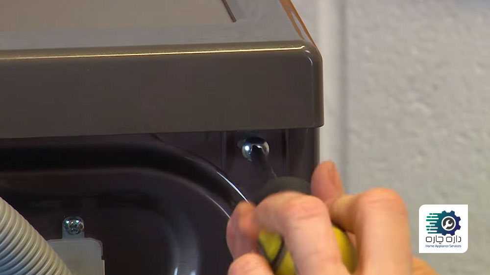 شخصی در حال بستن پیچ های پنل بالایی ماشین لباسشویی