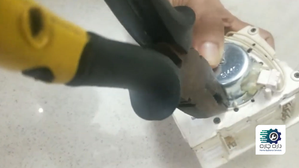 شخصی در حال آزاد کردن قفل های اطراف موتور تایمر ماشین لباسشویی