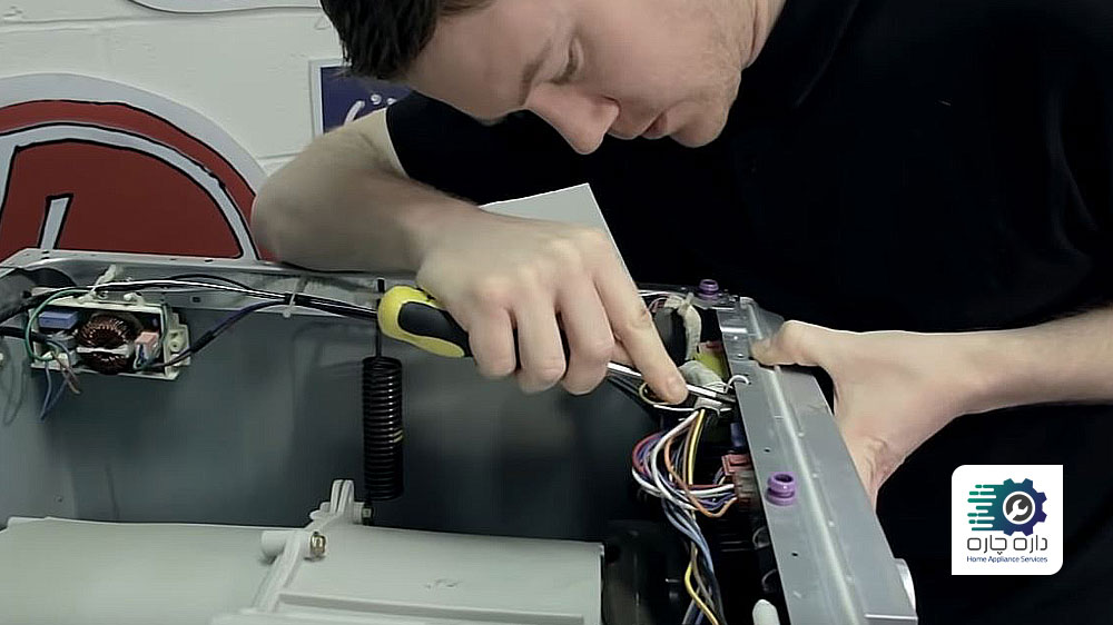 شخصی در حال آزاد کردن گیره های پنل جلویی ماشین لباسشویی