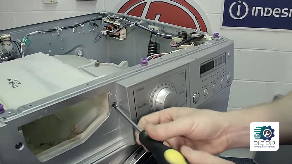 شخصی در حال باز کردن پیچ های پنل جلویی ماشین لباسشویی