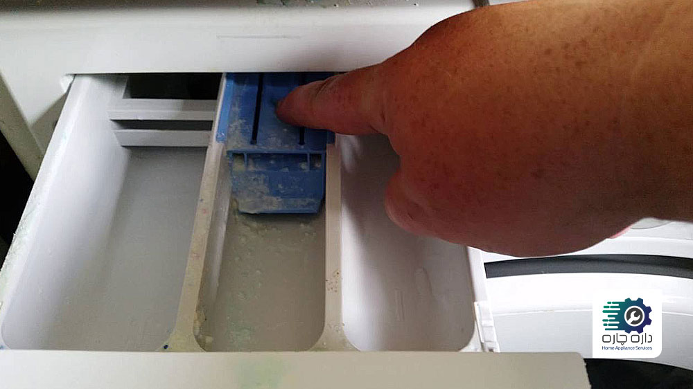 یک نفر در حال خارج کردن کشوی شوینده ماشین لباسشویی
