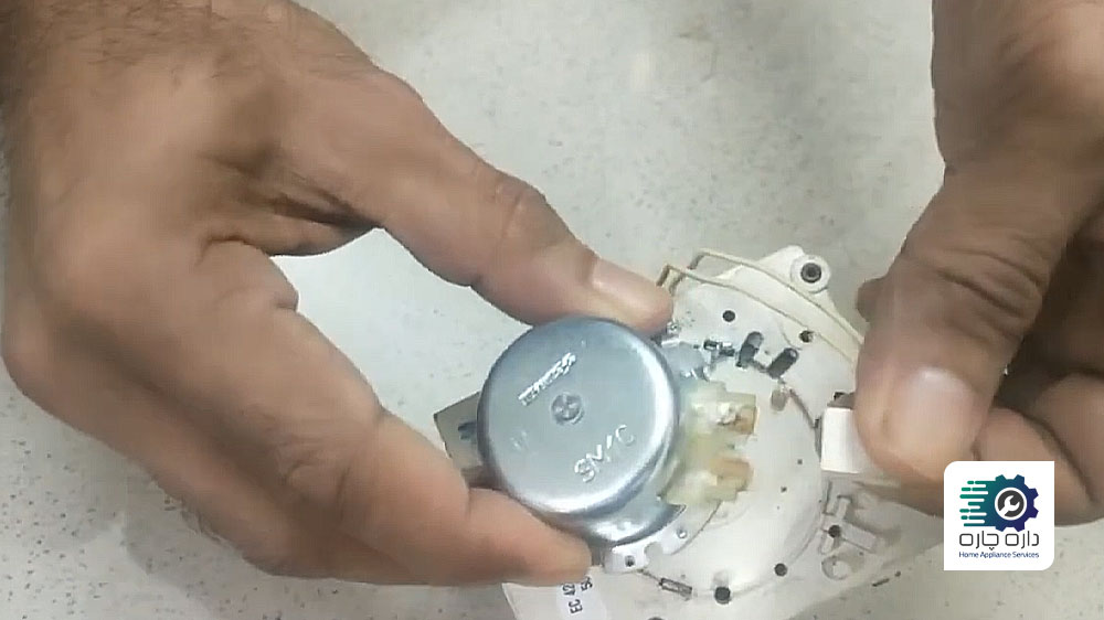 شخصی در حال جدا کردن کانکتور موتور تایمر ماشین لباسشویی