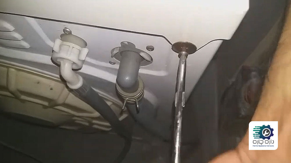 یک نفر در حال باز کردن پیچ پنل بالایی ماشین لباسشویی