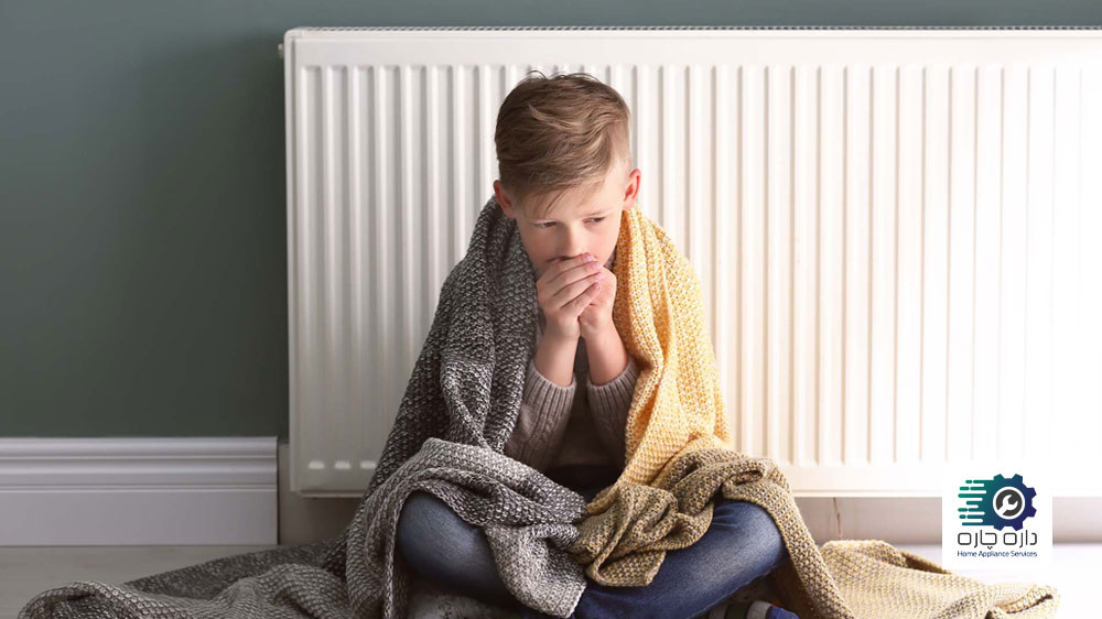 یک نفر در کنار رادیاتور نشسته و سردش است